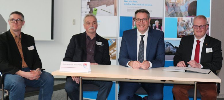 Projektleiter Christoph Biegel, Ortsbürgermeister Dieter Bretz, Minister Alexander Schweitzer und Bürgermeister Michael Holstein (von links nach rechts) bei der Unterzeichnung der Kooperationsvereinbarung zum Landesprojekt „WohnPunkt RLP“.
