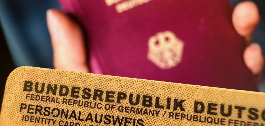 Bild eines Personalausweises - im Hintergrund unscharf ein Reisepass mit dem Bundesadler