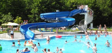 Schwimmbecken mit großer blauer geschwungener Half-Pipe-Rutsche