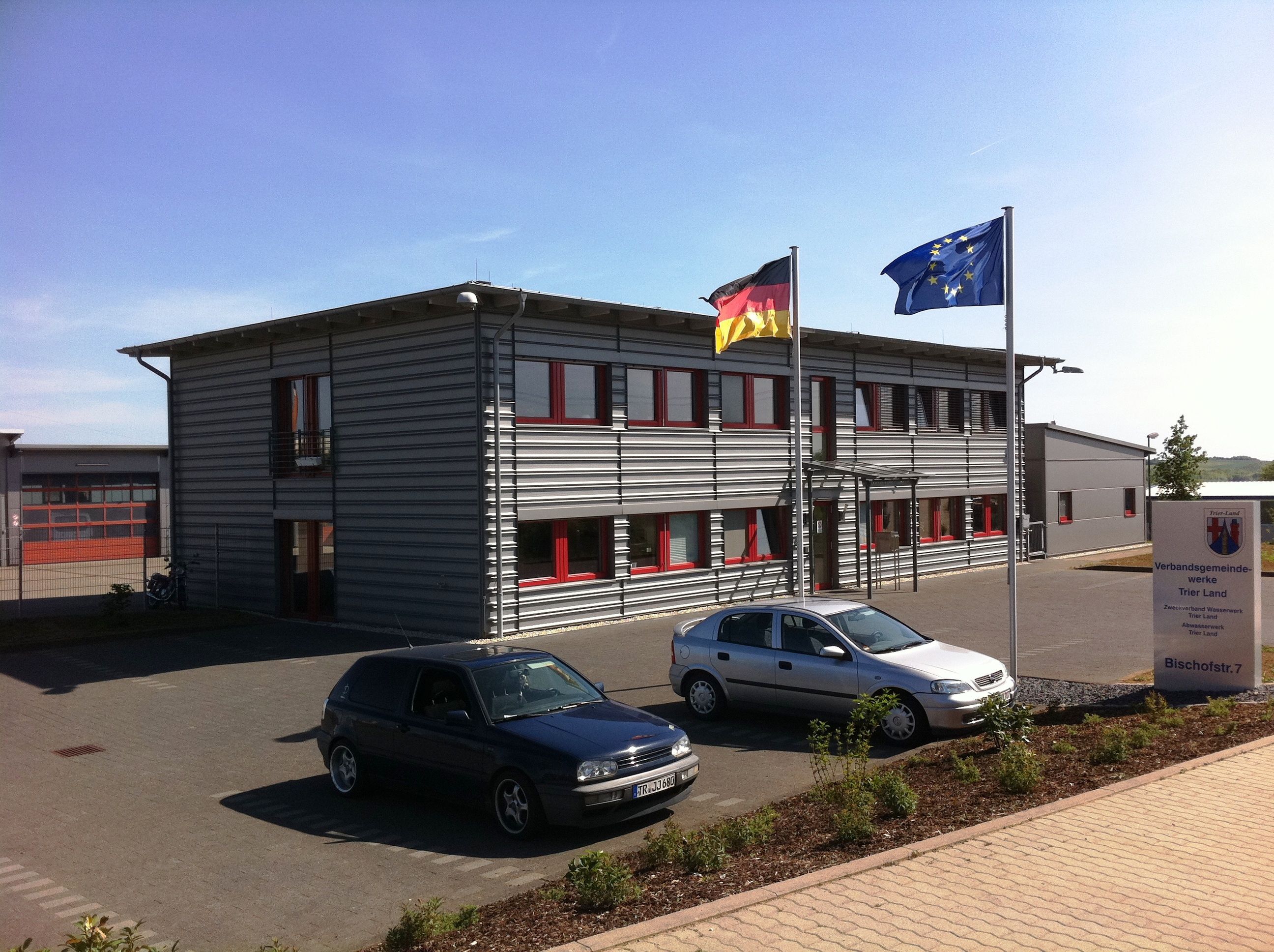 Gebäude des Technischen Dienstleistungszentrums Graues Flachdachgebäude des Technischen Dienstleistungszentrums mit Flaggen vor der Eingangstür