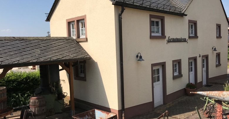 Heimatmuseum mit alten Landwirtschaftsgeräten vor dem Eingang
